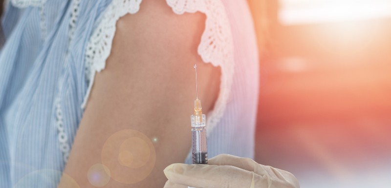 Vaccine syringe ready to be injected into a girl's arm